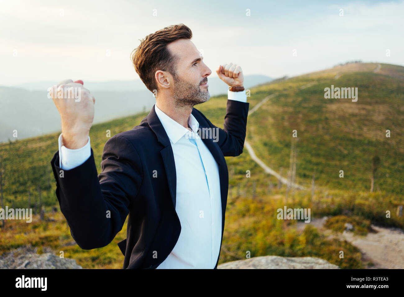 Sicuro di sé imprenditore permanente sulla cima di una montagna Foto Stock