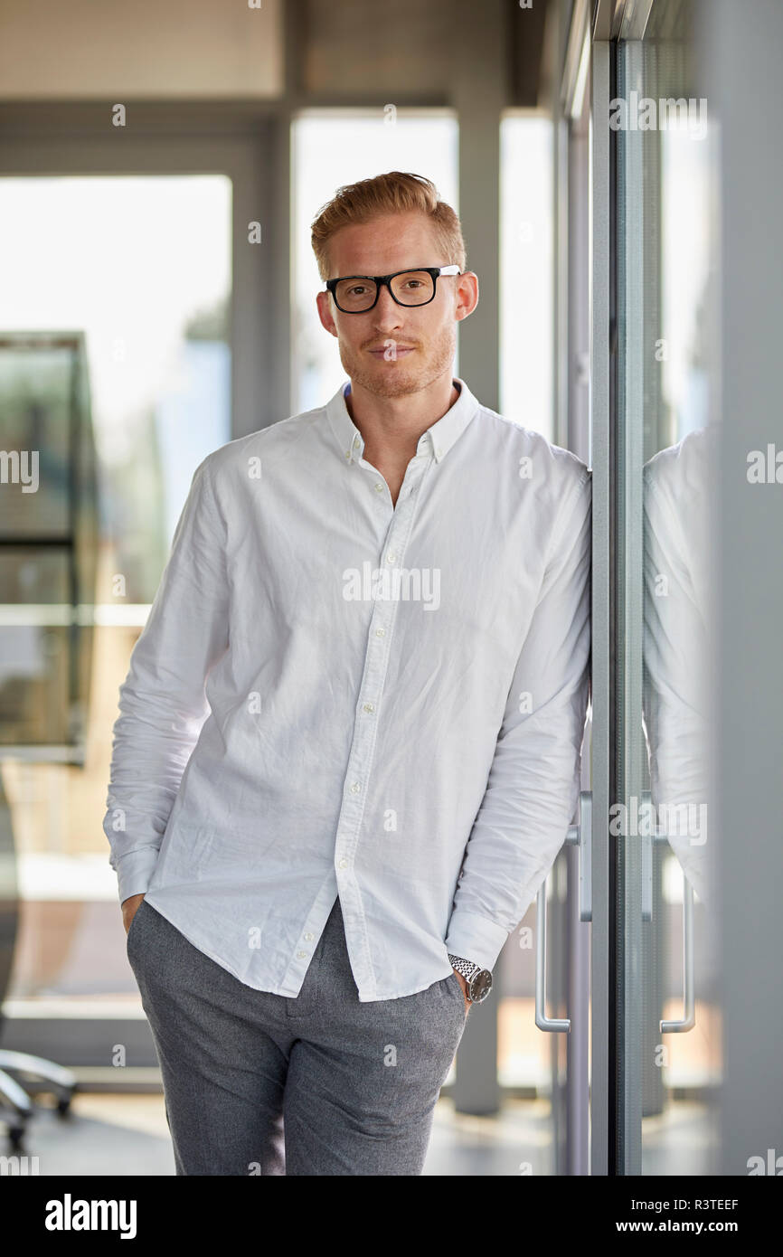 Ritratto di imprenditore fiducioso in office appoggiata contro la finestra Foto Stock
