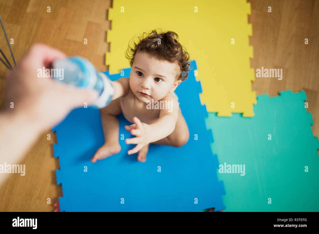 Mano del Padre dando baby boy una bottiglia di acqua Foto Stock