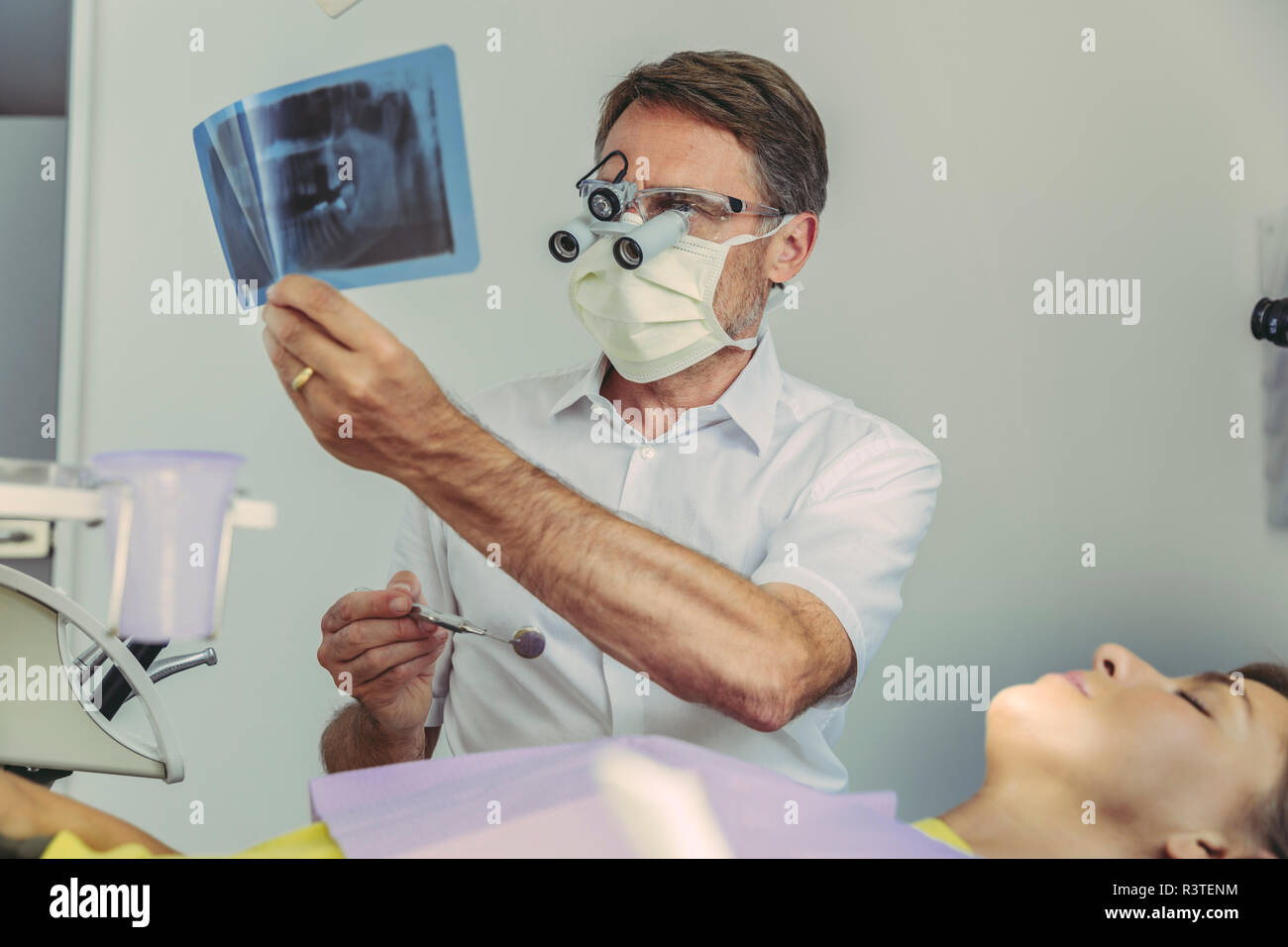 Dentista guardando immagine a raggi x prima del trattamento Foto Stock