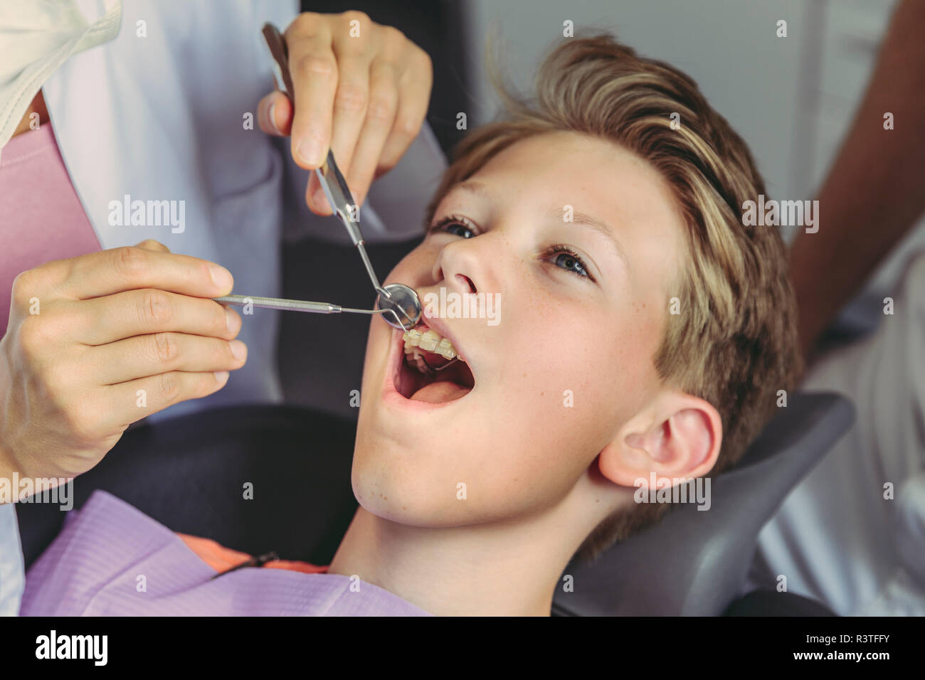 Dentista esaminando boy i denti con strumenti dentali Foto Stock