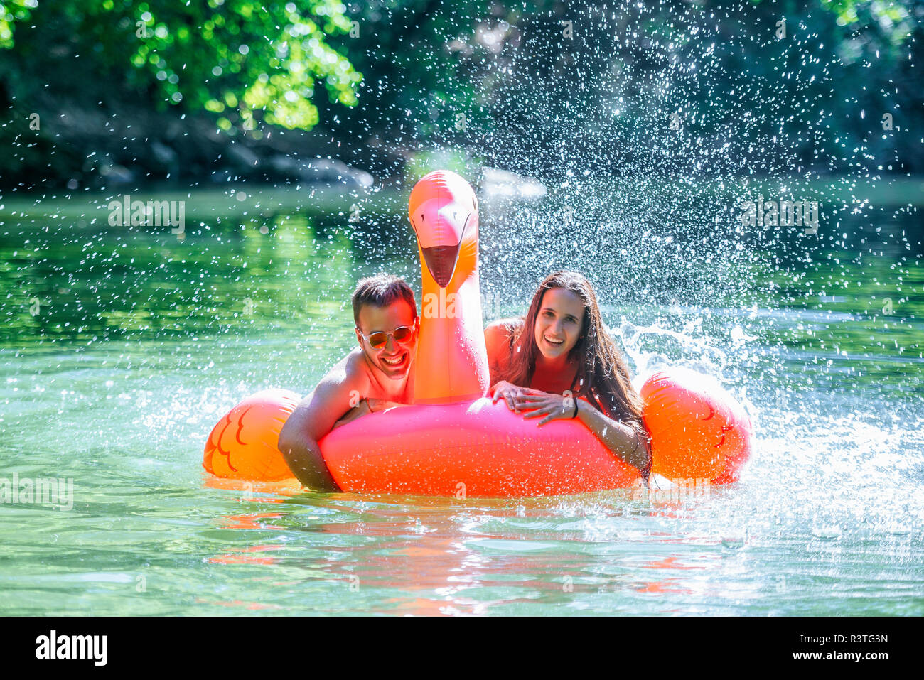 Giovane galleggiante sull'acqua su un gonfiabile flamingo Foto Stock