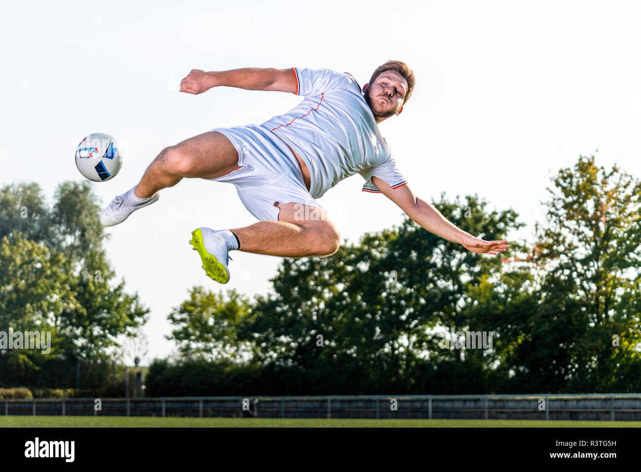 Giovane uomo calci palla calcio Foto Stock