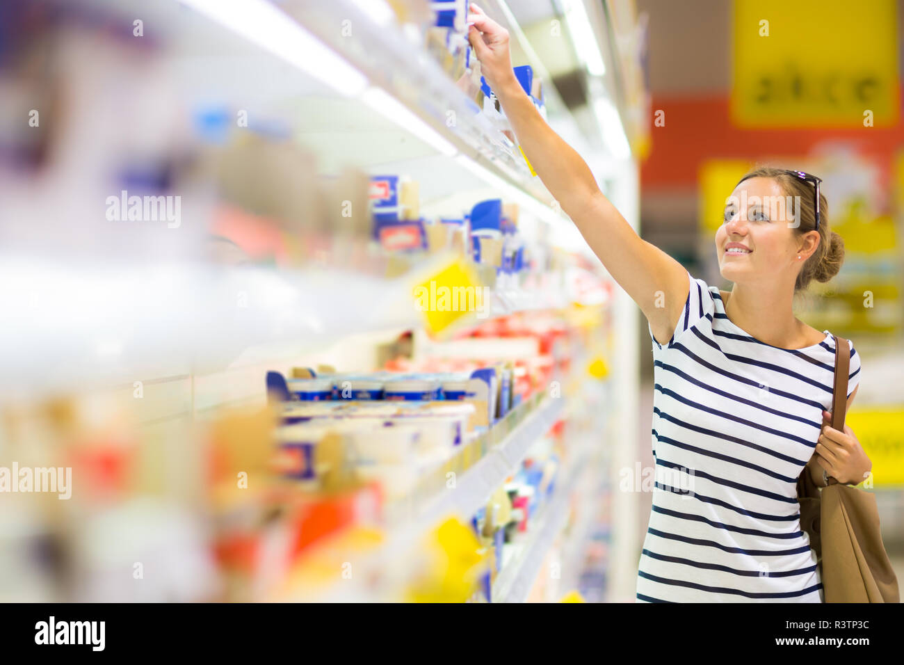 Bella giovane donna shopping per prodotti caseari presso un negozio di alimentari/supermercato (toni di colore immagine) Foto Stock