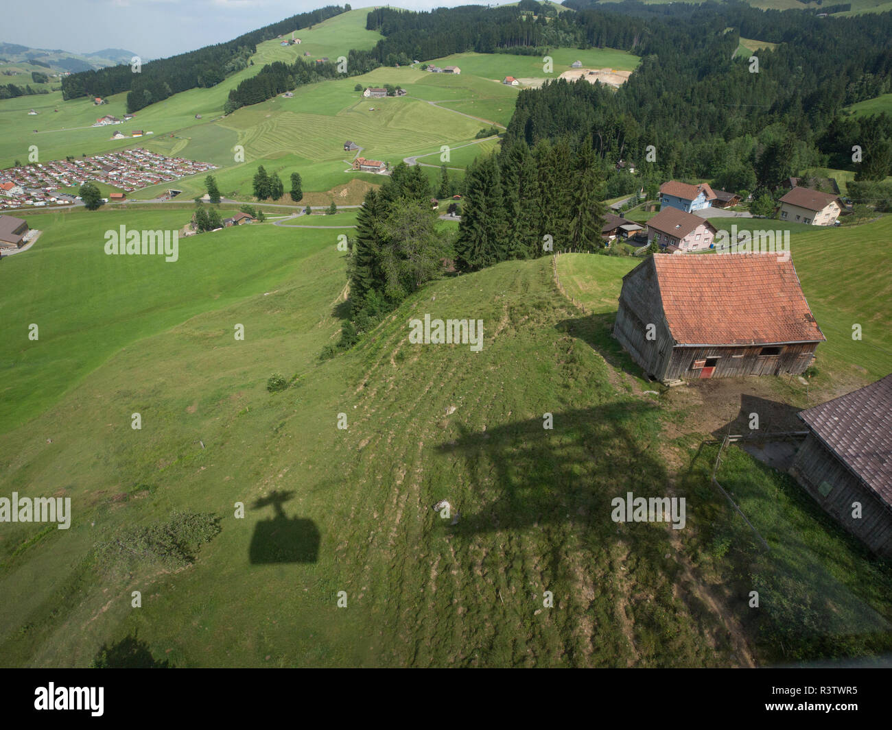 Ombra di ski lift in gondola lungo i pascoli verdi della Svizzera Foto Stock