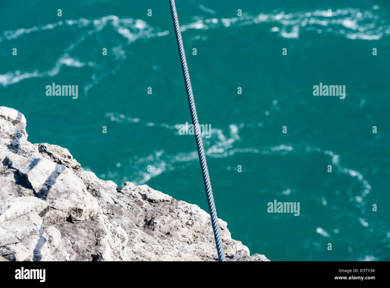 Tenuta del cavo di acciaio oltre il bordo del rock e del fiume Foto Stock