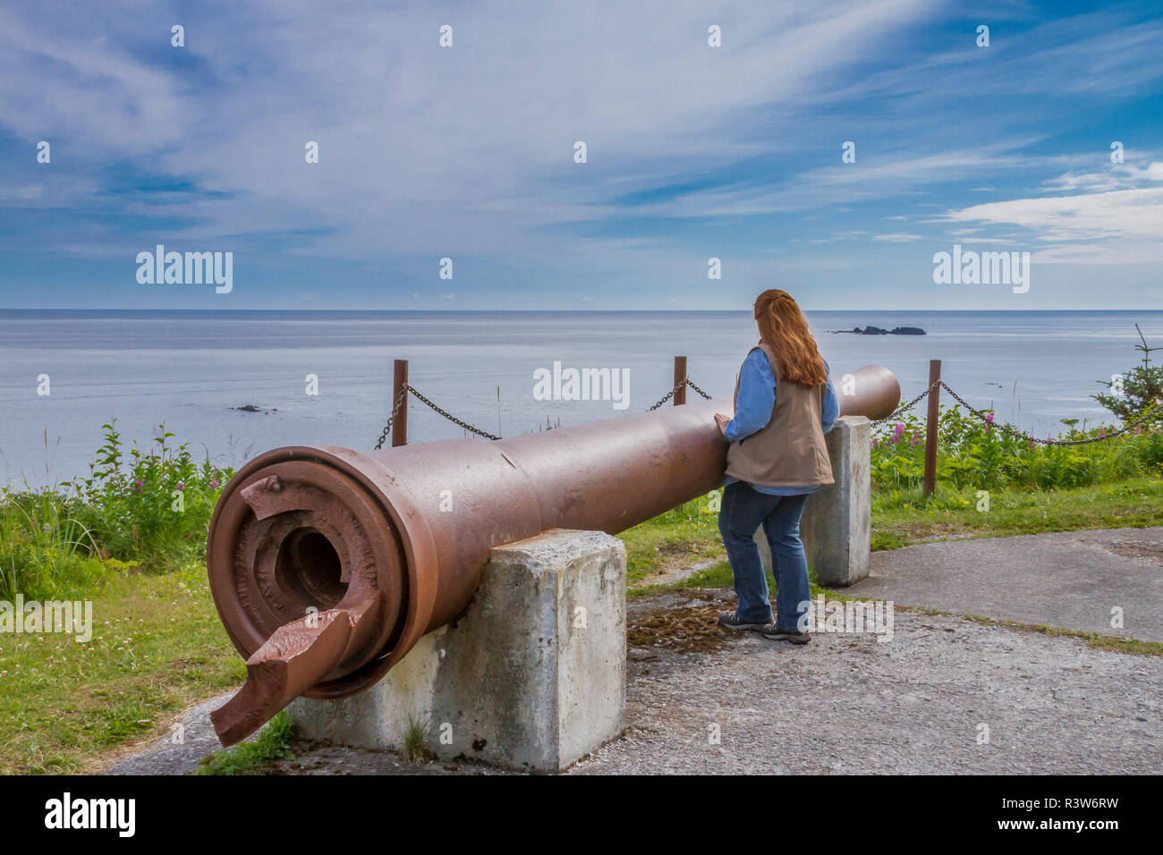 Stati Uniti d'America, Alaska, Kodiak. Donna godendo la vista dal punto di Miller a 8 pollici canna di fucile dall'artiglieria durante la seconda guerra mondiale a Fort Abercrombie. (MR) Foto Stock