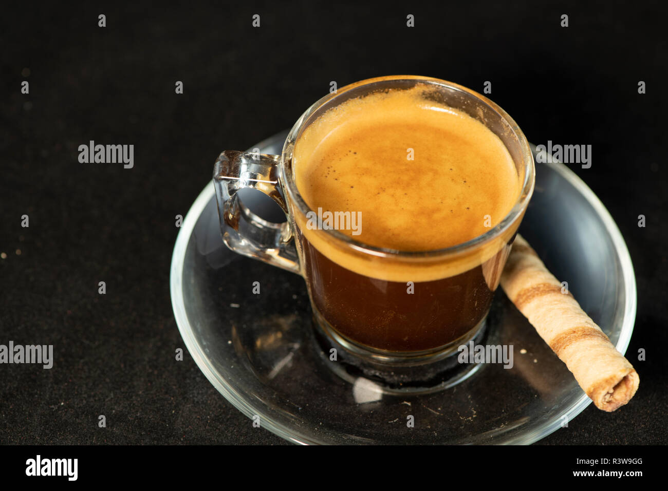 Doppio espresso e rullo di wafer con isolati su sfondo nero Foto Stock