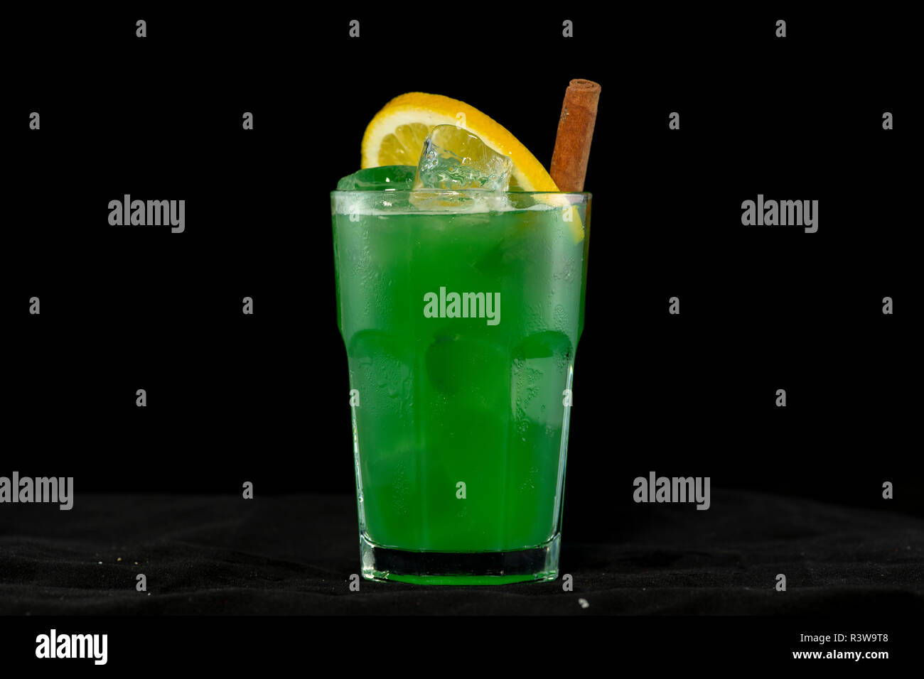 Cocktail verde verde con succhi di frutta, alcol e uno spicchio di lime con isolati su sfondo nero Foto Stock