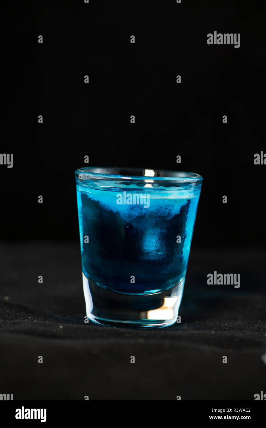 Medusa shot cocktail con curacao blu, sambuca, vodka e latte isolate con sfondo nero Foto Stock