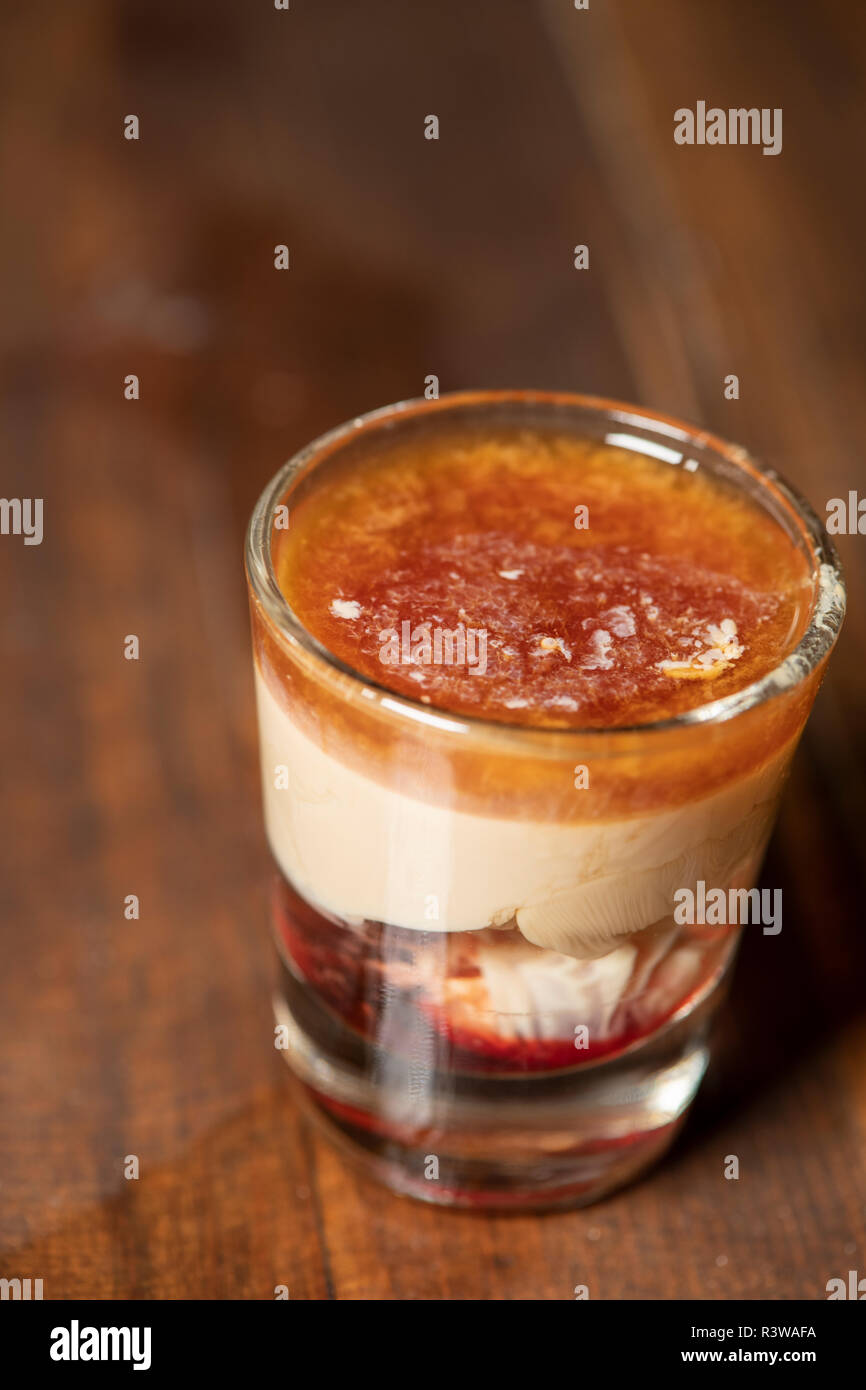 Emorragia cerebrale shot cocktail con schnapps, baileys Irish cream e grenadine con uno sfondo di legno Foto Stock