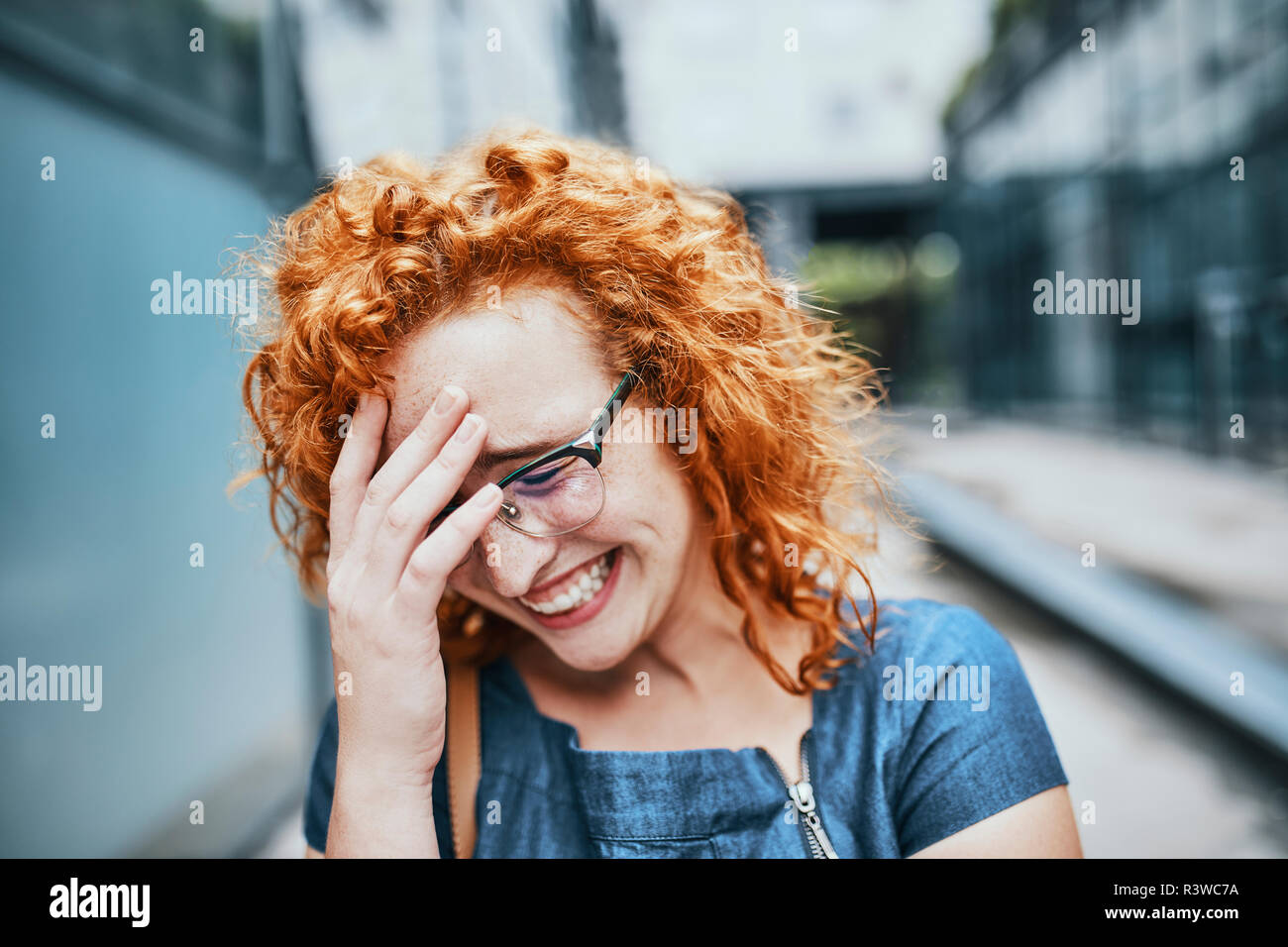Ritratto di una giovane donna redheaded indossando occhiali, sorridente Foto Stock