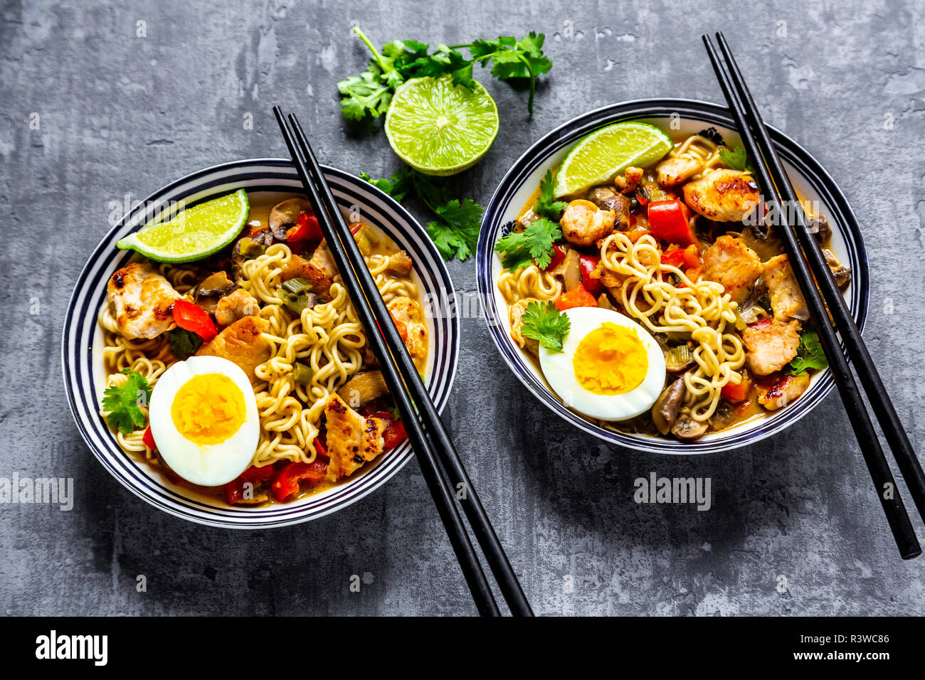 Ramen zuppa con uovo, tagliatelle, carne di pollo, paprica, fungo, cipolline, lime e coriandolo Foto Stock