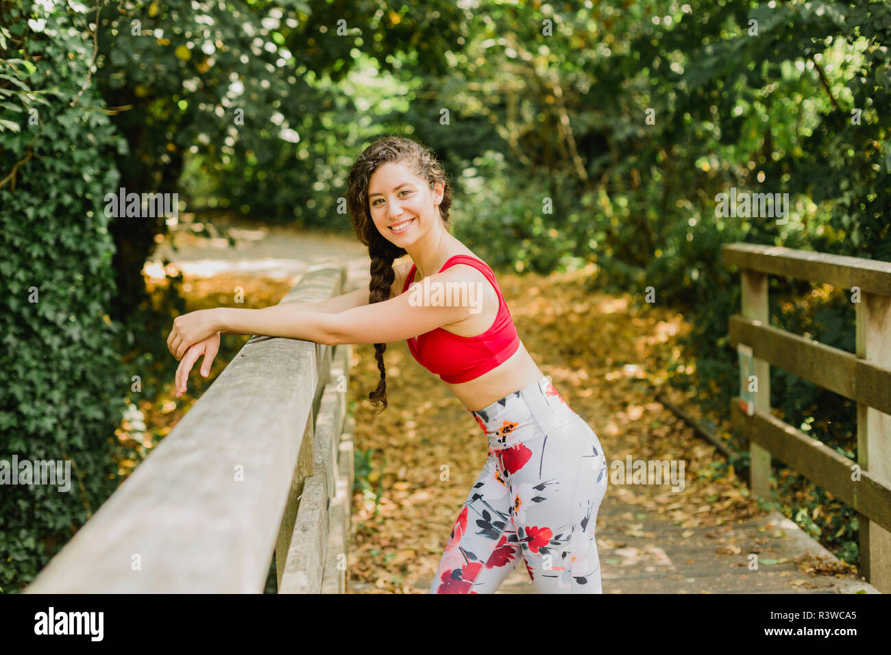 Giovane donna sorridente durante la pausa dopo la pratica di Pilates in un parco urbano Foto Stock