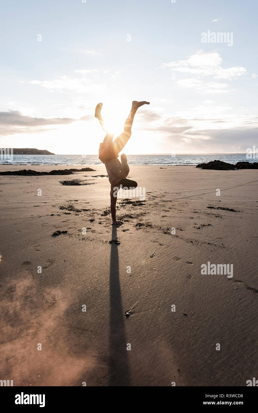 Uomo che fa del movimento di formazione presso la spiaggia al tramonto Foto Stock