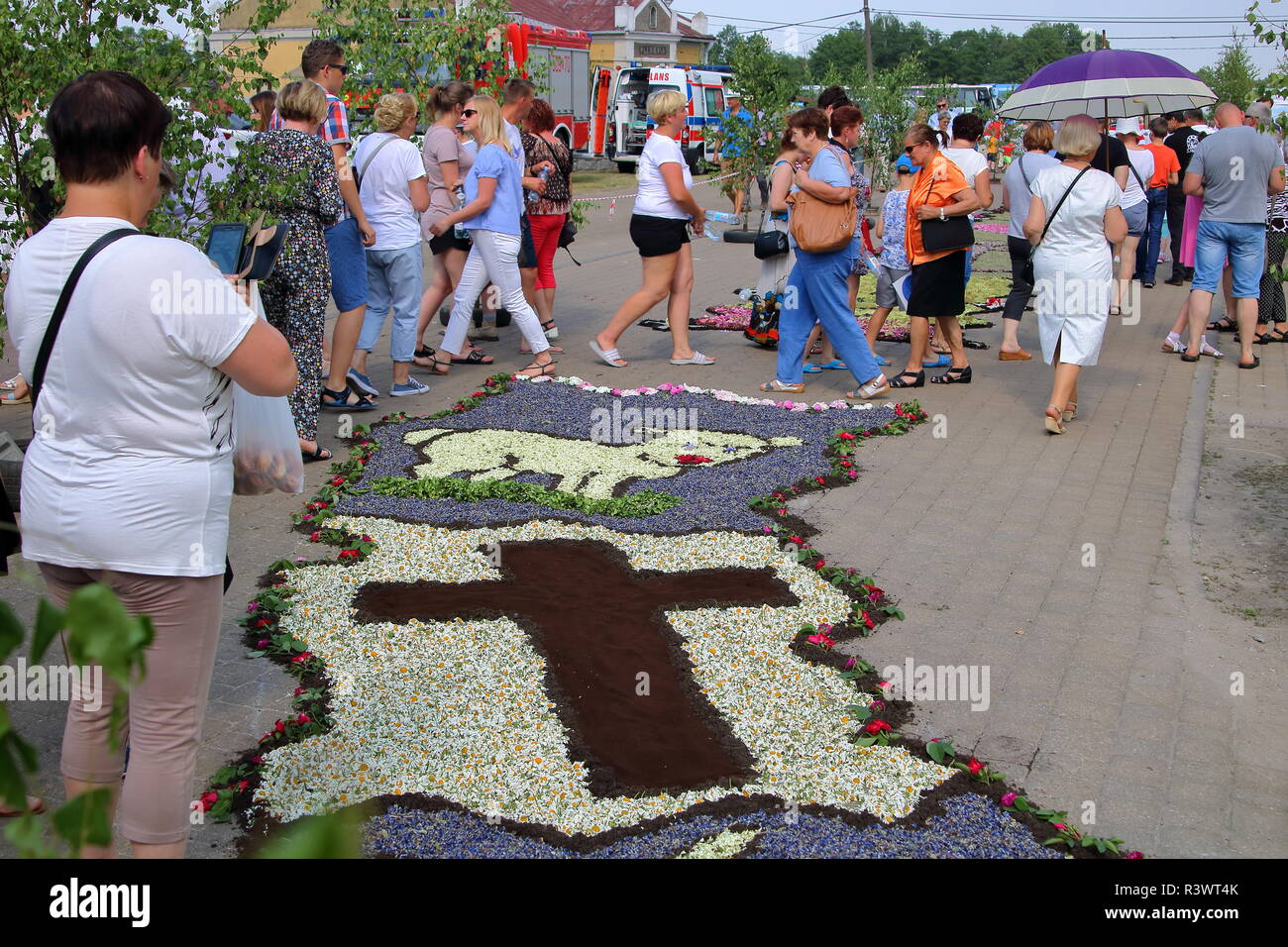 La gente camminare lungo e guardare bellissimo tappeto floreale realizzato ogni anno in Spycimierz, Polonia, per celebrare il Corpus Domini vacanza. Foto Stock