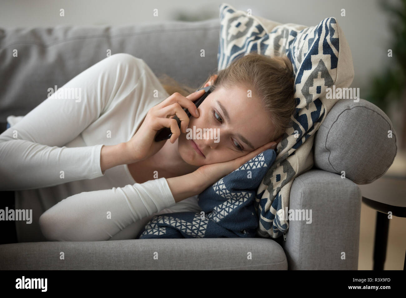 Sconvolto ragazza distesa sul lettino avente spiacevoli telefono talk Foto Stock