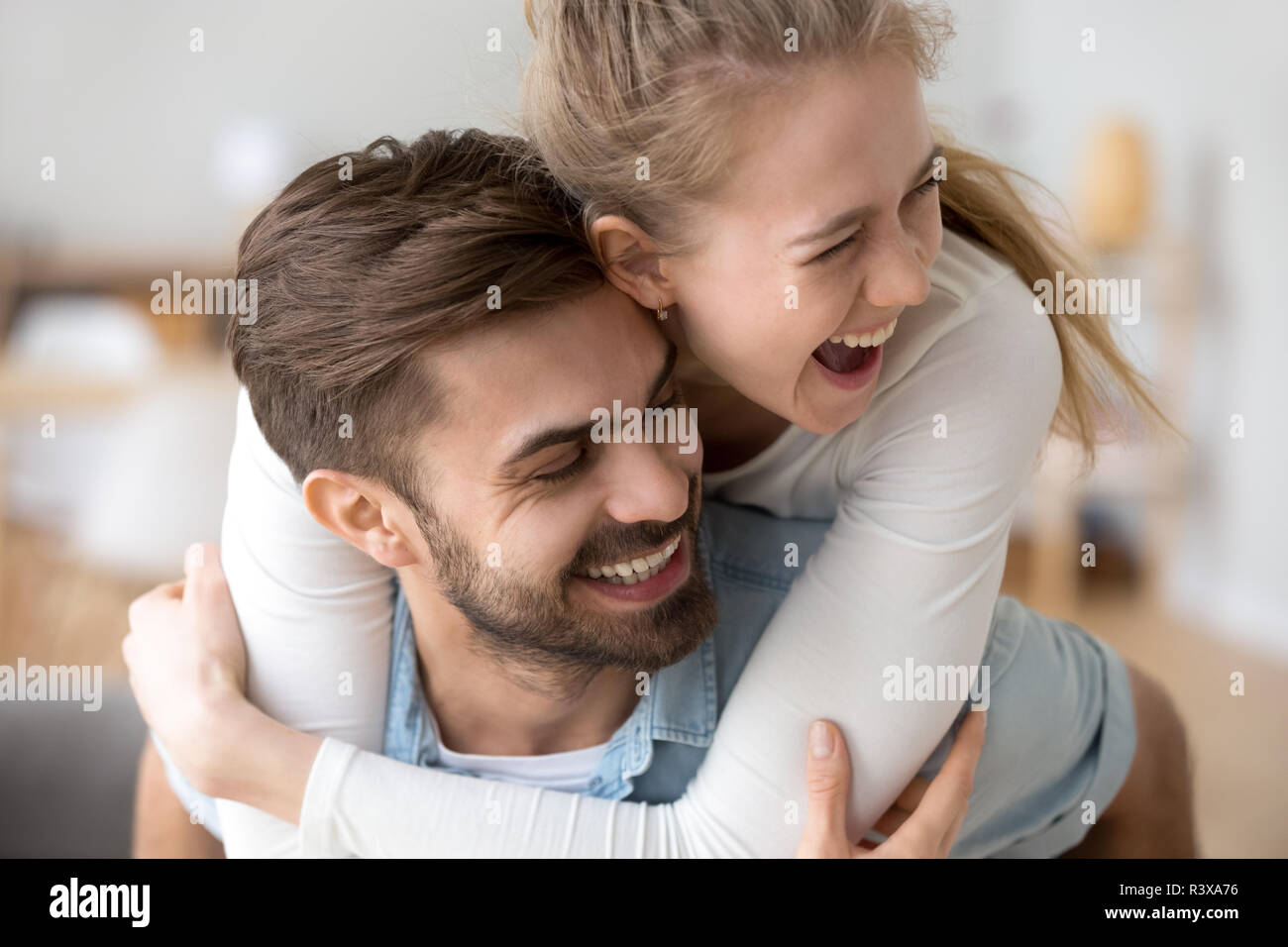 Donna felice piggyback amorevole fidanzato divertirsi a casa Foto Stock