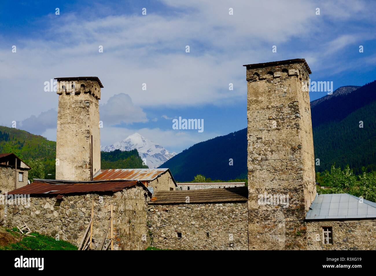 Una vista di due torri di guardia con Snow capped picco di montagna nella distanza, Mestia. La Georgia Foto Stock