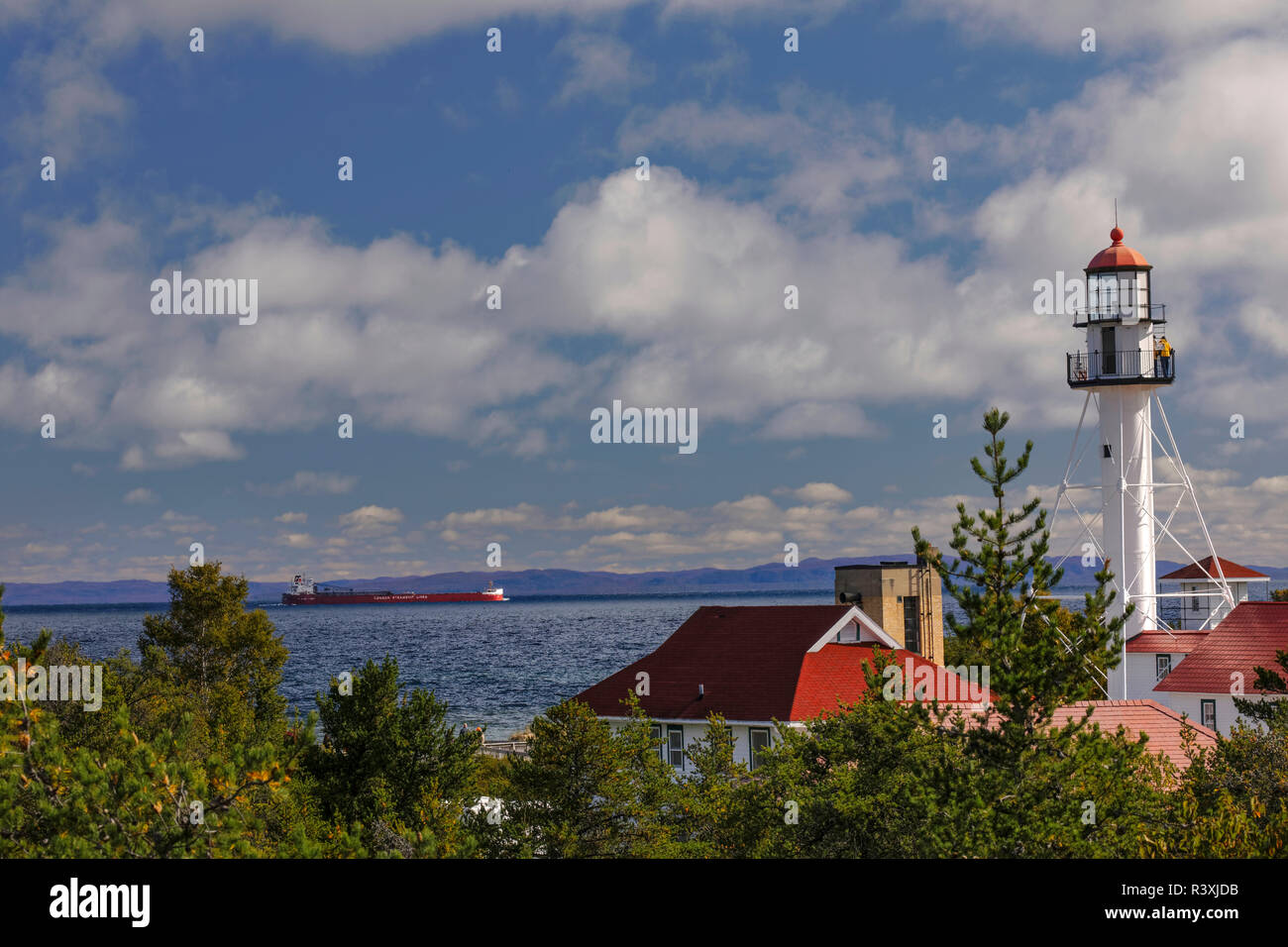 Freighter legato per il Canada passando il coregone Point Lighthouse, la più antica luce di funzionamento sul lago Superiore, Penisola Superiore, Michigan Foto Stock
