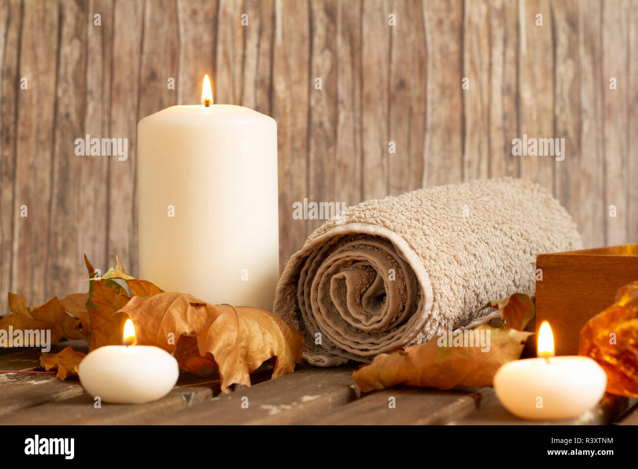 Candele accese e l'asciugamano in spa su uno sfondo di legno Foto Stock