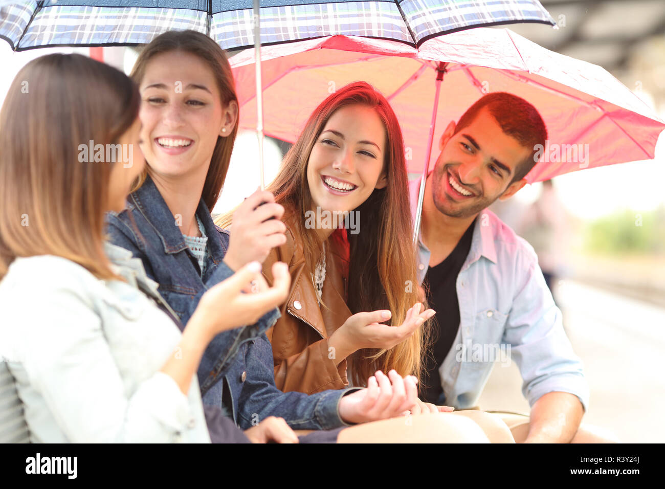Quattro amici parlando all'aperto in un giorno di pioggia Foto Stock
