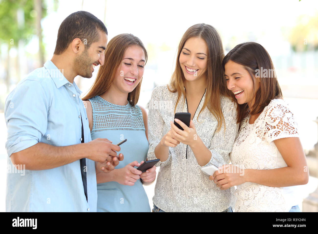 Quattro amici a guardare i social media in uno smart phone Foto Stock