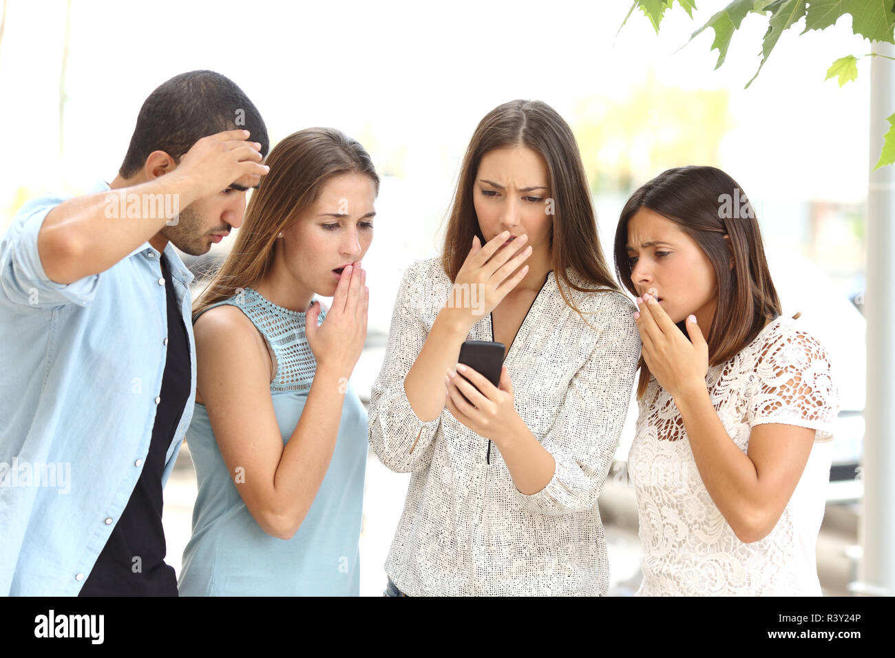 Quattro amici preoccupati guardando smart phone Foto Stock