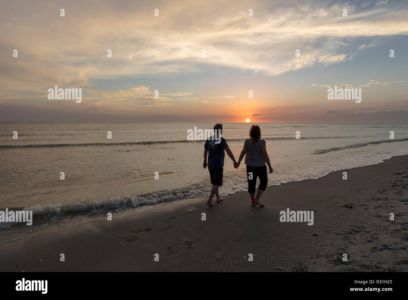 Giovane tenendo le mani al tramonto lungo il Golfo del Messico in Sanibel Island, Florida, Stati Uniti d'America (MR) Foto Stock