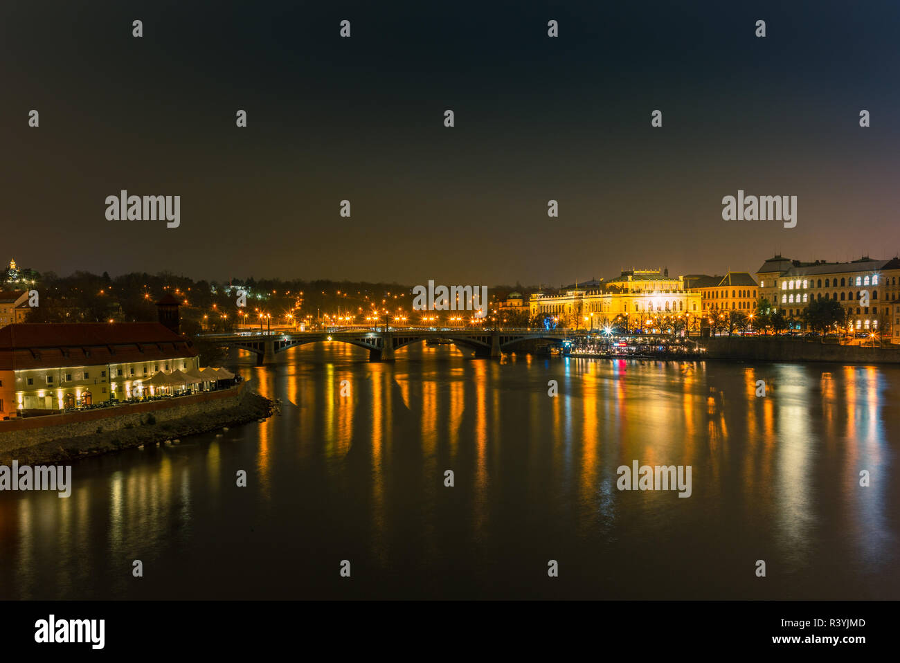 Illuminata edifici classici e le luci di strada riflettendo sul fiume Moldava a Praga in una fredda notte invernale - 1 Foto Stock