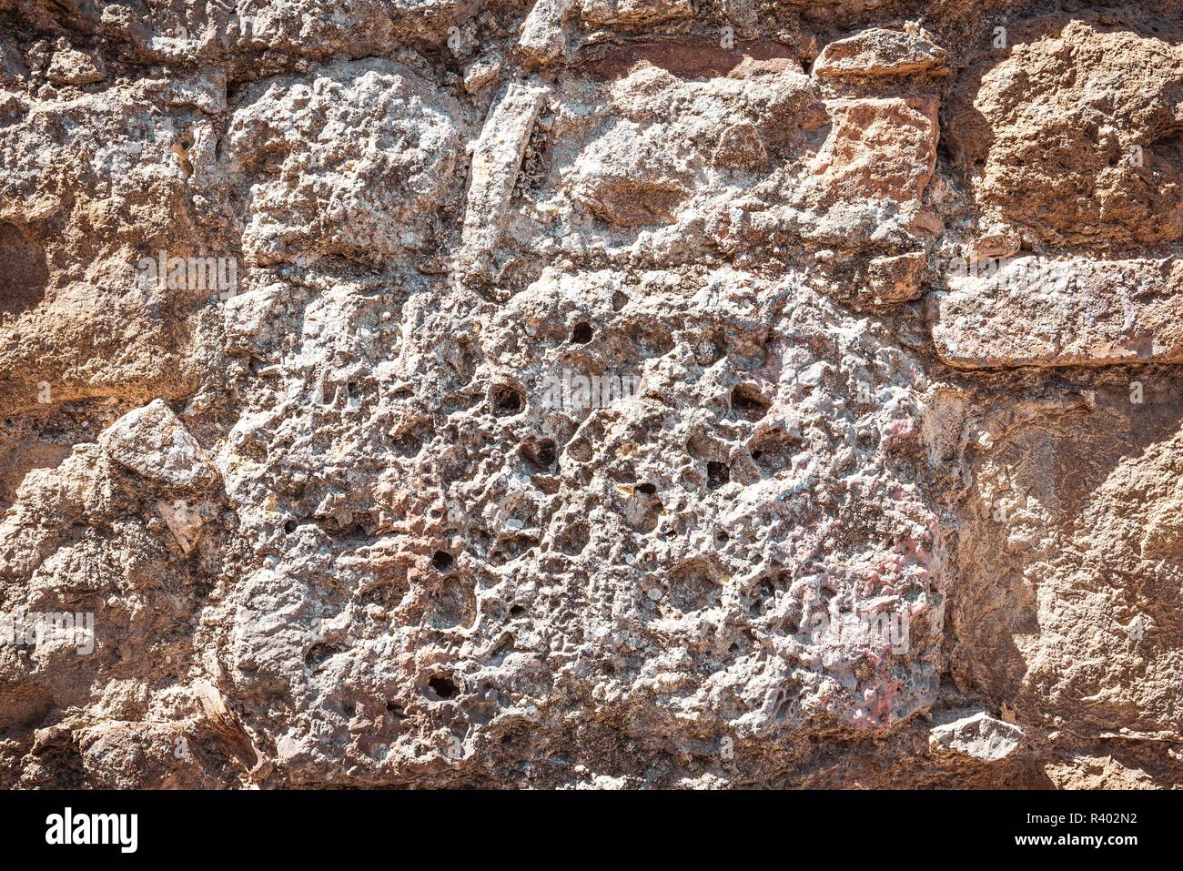 Foto orizzontale con la texture delle antiche mura. Muro è costruito da pietre e mattoni. Mattoni sono di colore arancione e marrone e notevolmente usurata. Le pietre sono ve Foto Stock