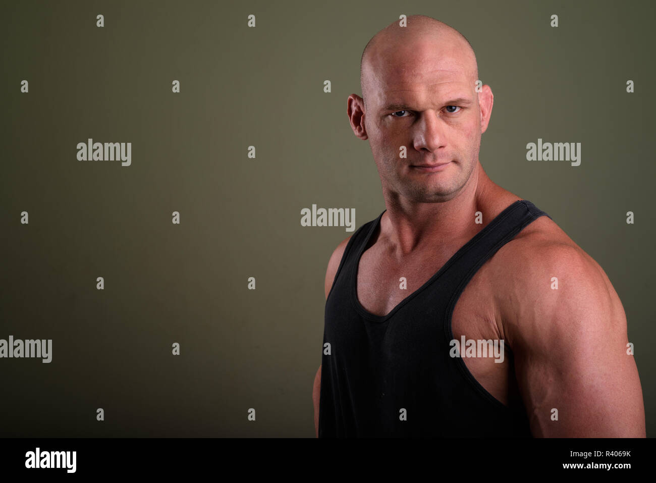 Bald muscolare di uomo che indossa tank top contro sfondo colorato Foto Stock