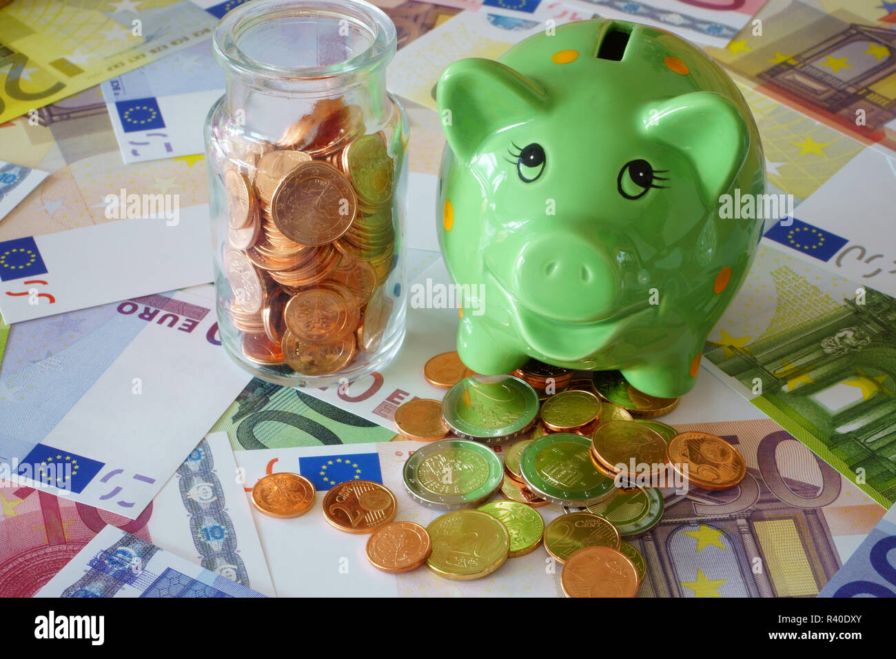 Salvadanaio e vetro con le monete in euro in banconote Foto Stock
