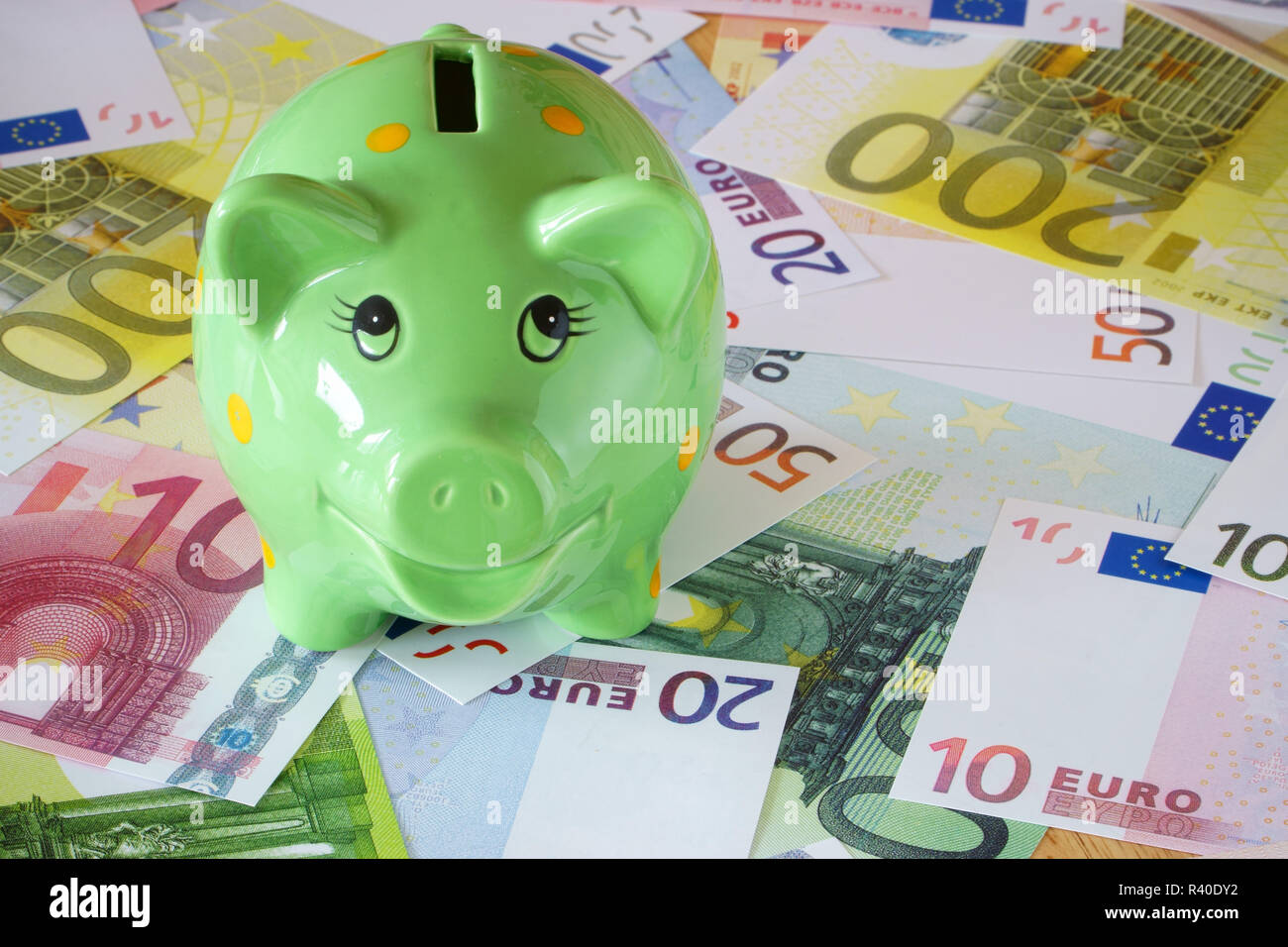Green salvadanaio e banconote in euro sul tema delle finanze Foto Stock