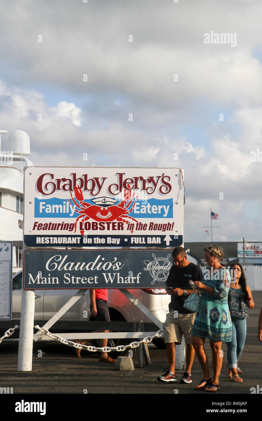 La gente a piedi passato indicazioni per ristoranti di pesce in Greenport, Long Island, New York, Stati Uniti d'America. Foto Stock
