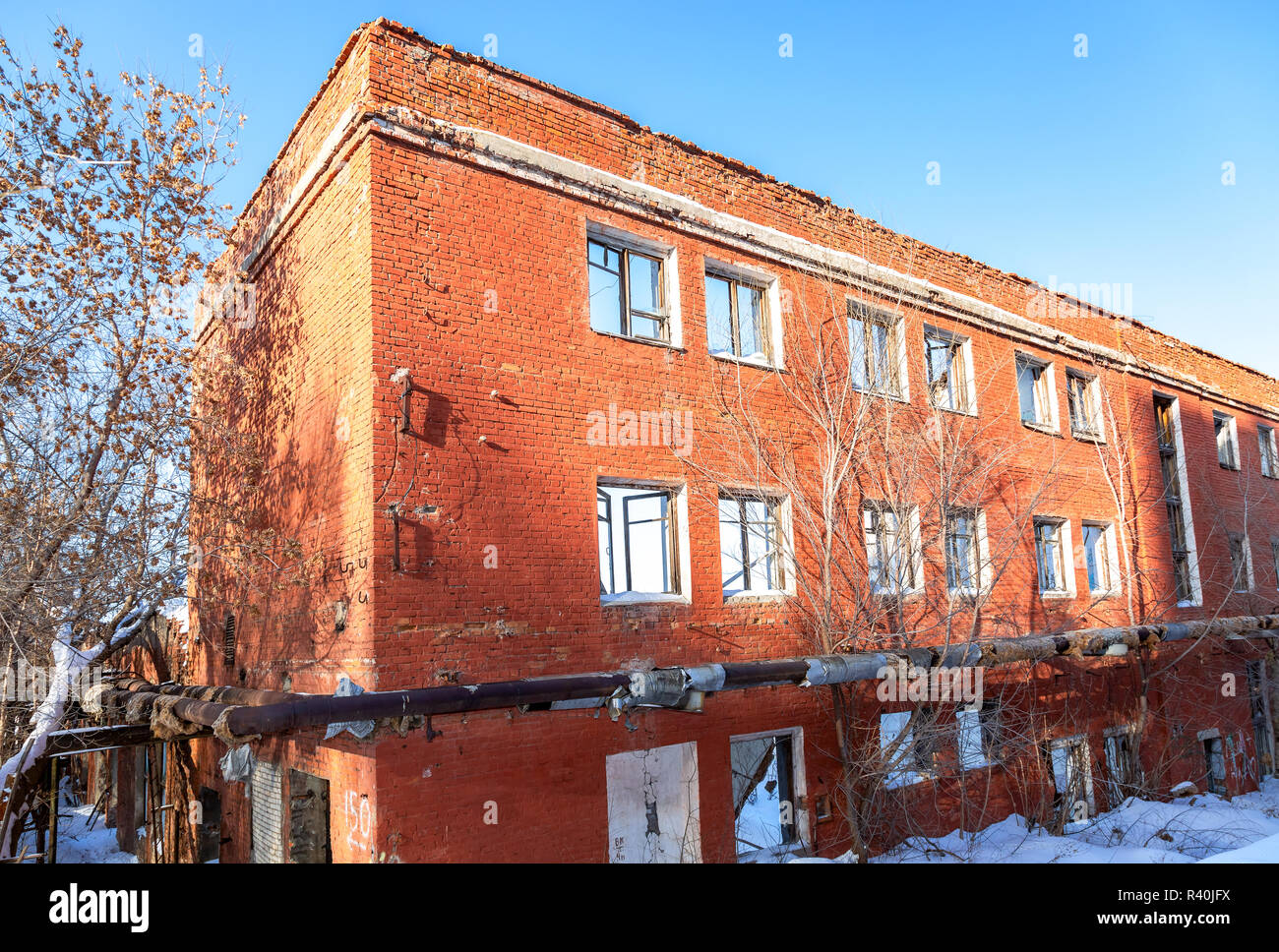 Vecchio e abbandonato edificio distrutto dal rosso mattone contro un cielo blu in giornata invernale Foto Stock