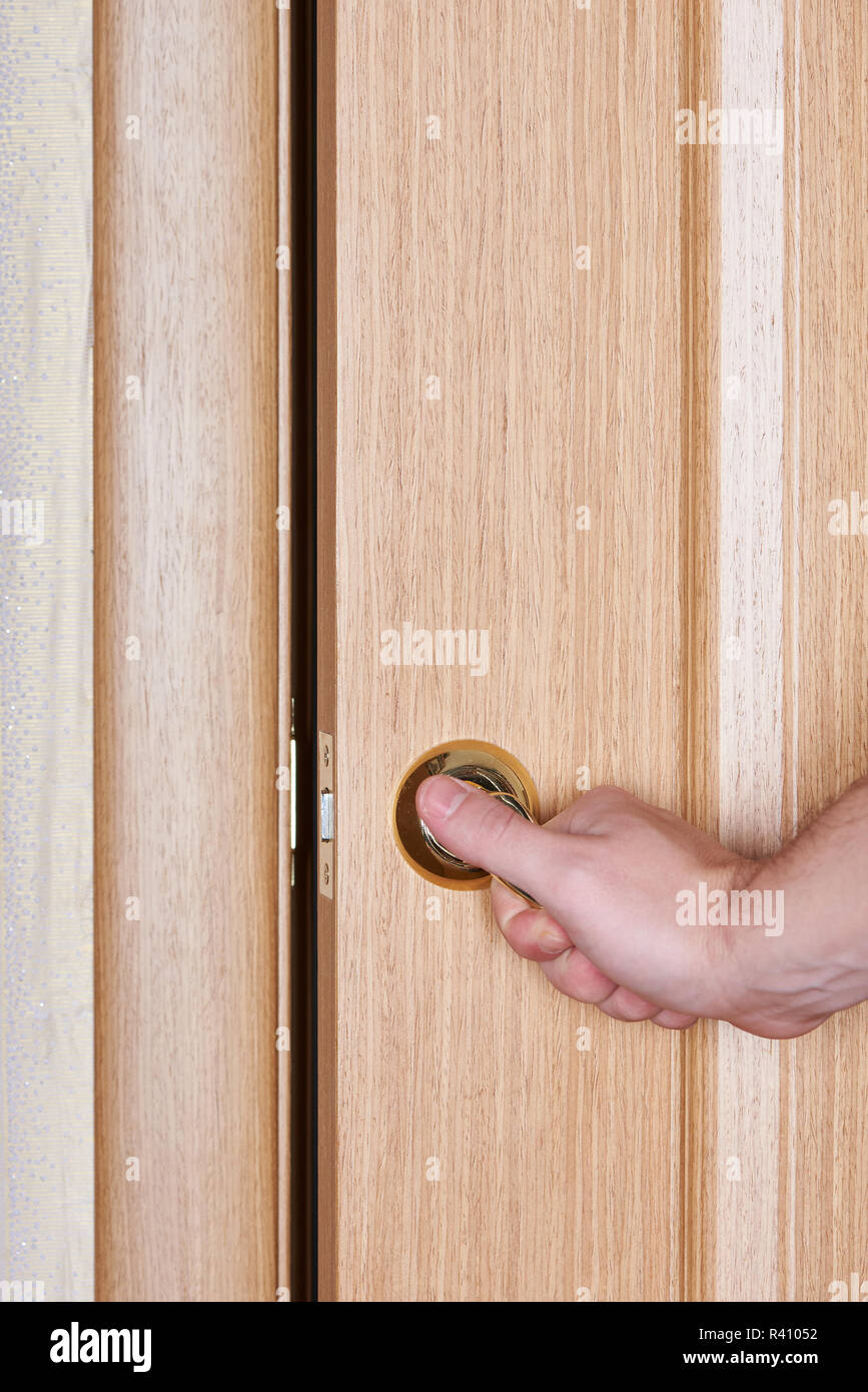 La chiusura della porta di legno di close-up. Chiudere a mano porta in legno con maniglia dorata Foto Stock