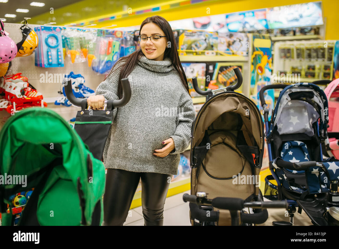Donna incinta scegliendo passeggino bimbo in un negozio di prodotti per  bambini. Futura madre cercando sul passeggino per il suo bambino, trasporto  di neonati Foto stock - Alamy