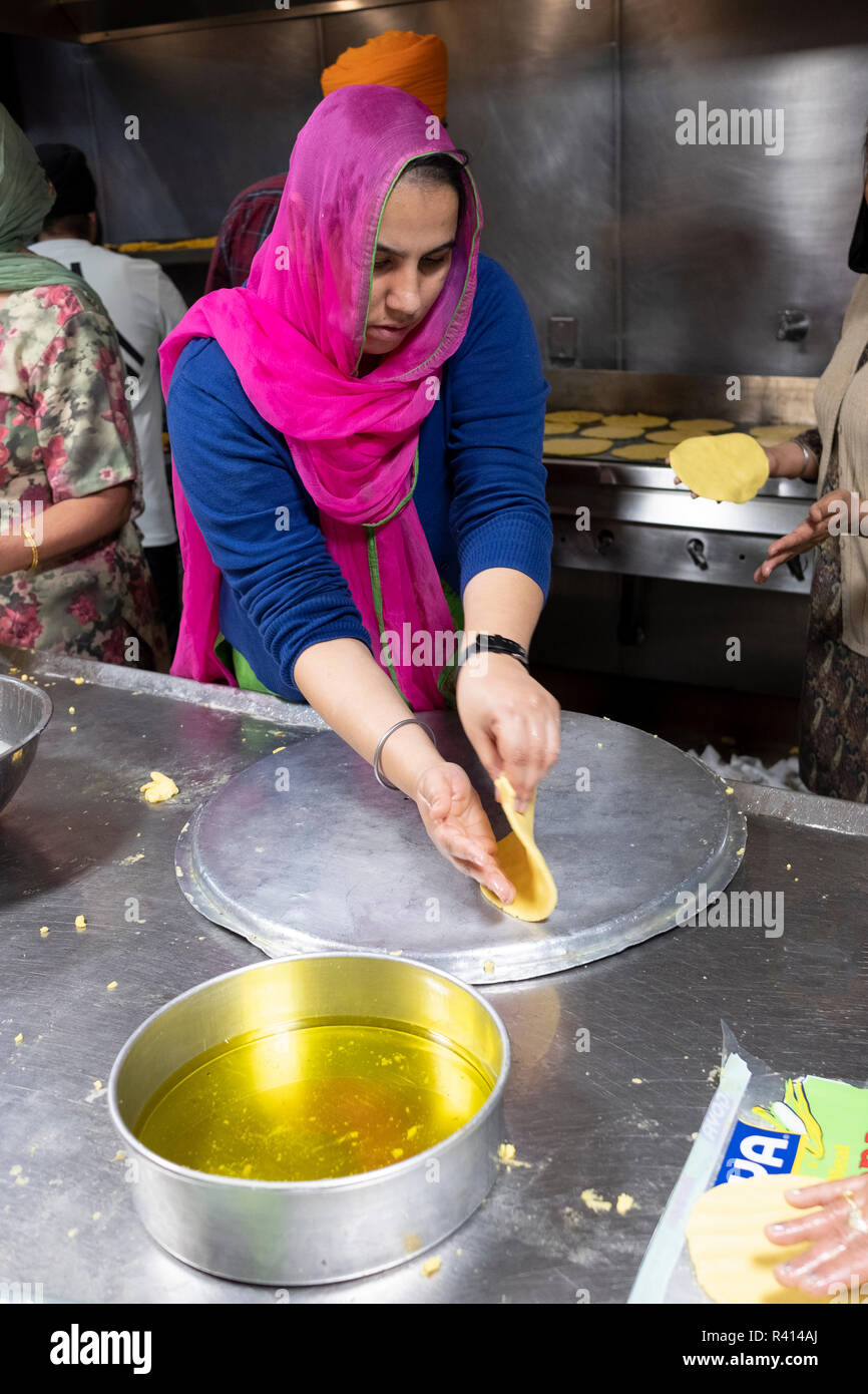 La religione sikh donna ad una langar - cucina comune - la laminazione a mano roti pane. A un tempio nel Queens, a New York City. Foto Stock