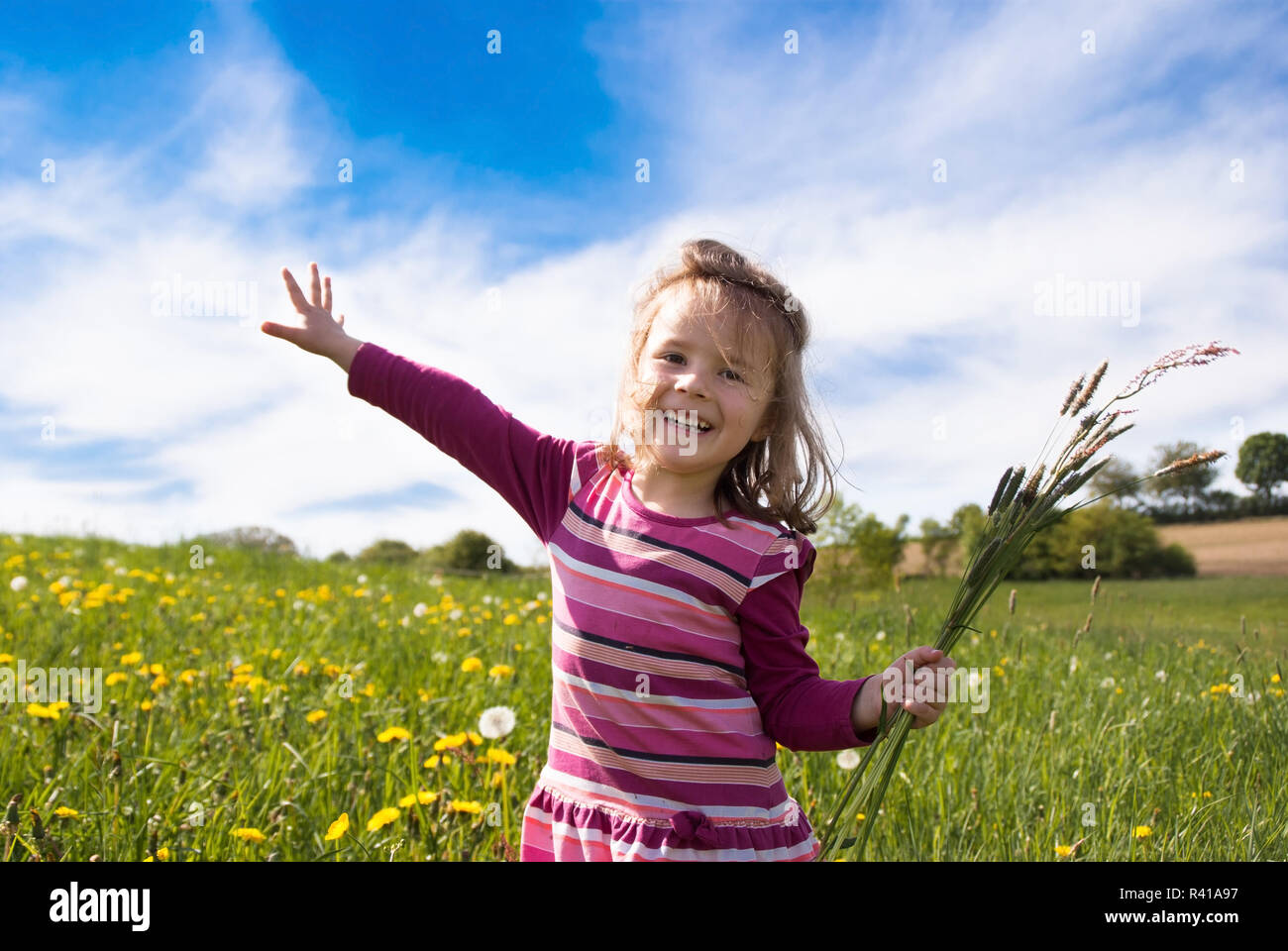 Una bambina volare con un ciuffo di erba su un prato a molla Foto Stock