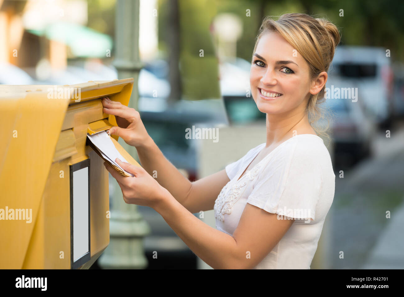 Donna inserendo la lettera nella cassetta postale Foto Stock