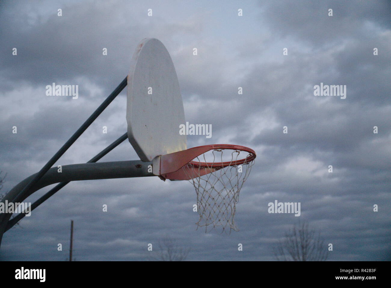 Un rosso e bianco Basketball hoop davanti a un cielo nuvoloso. Foto Stock