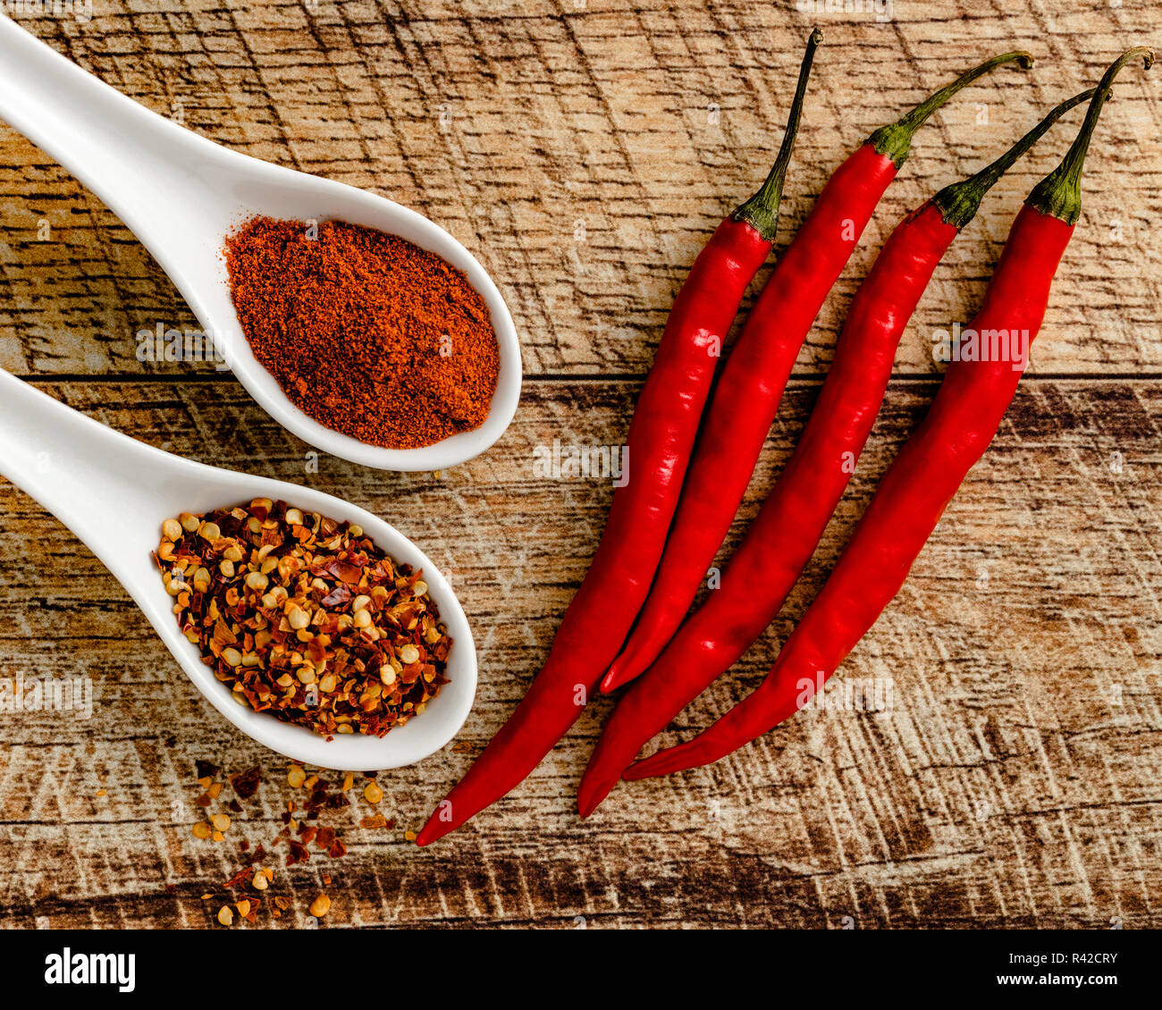 Peperoni di Caienna con massa cayenne e pepe rosso flake su una tavola di legno di sfondo Foto Stock