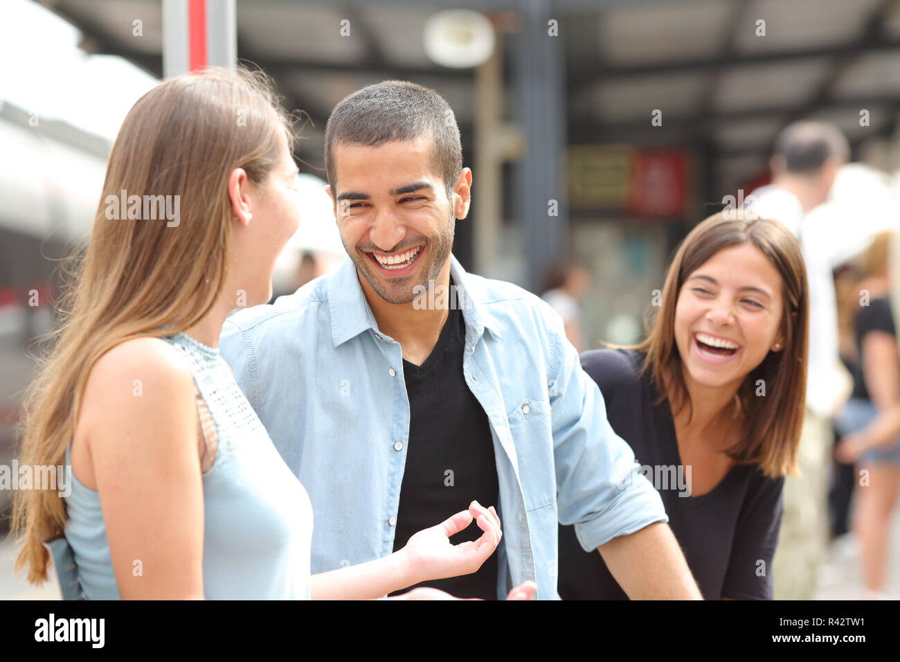 Tre amici a parlare e ridere in una stazione ferroviaria Foto Stock