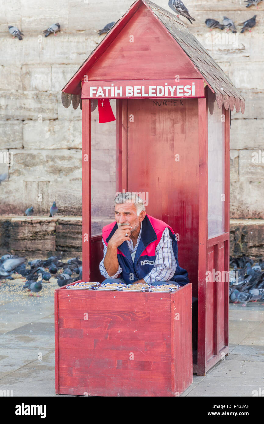 Istanbul, Turchia, Settembre 19, 2013: uomo vendita di cibo di piccione da uno stand al di fuori della nuova moschea nel quartiere Eminonu. Foto Stock