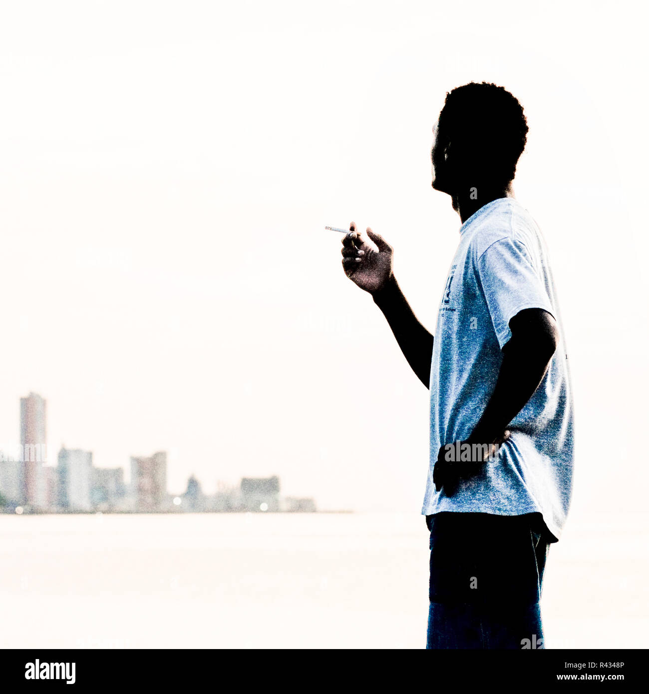 Cuba, La Habana, tramonto sul Malecon, giovane fumatore Foto Stock