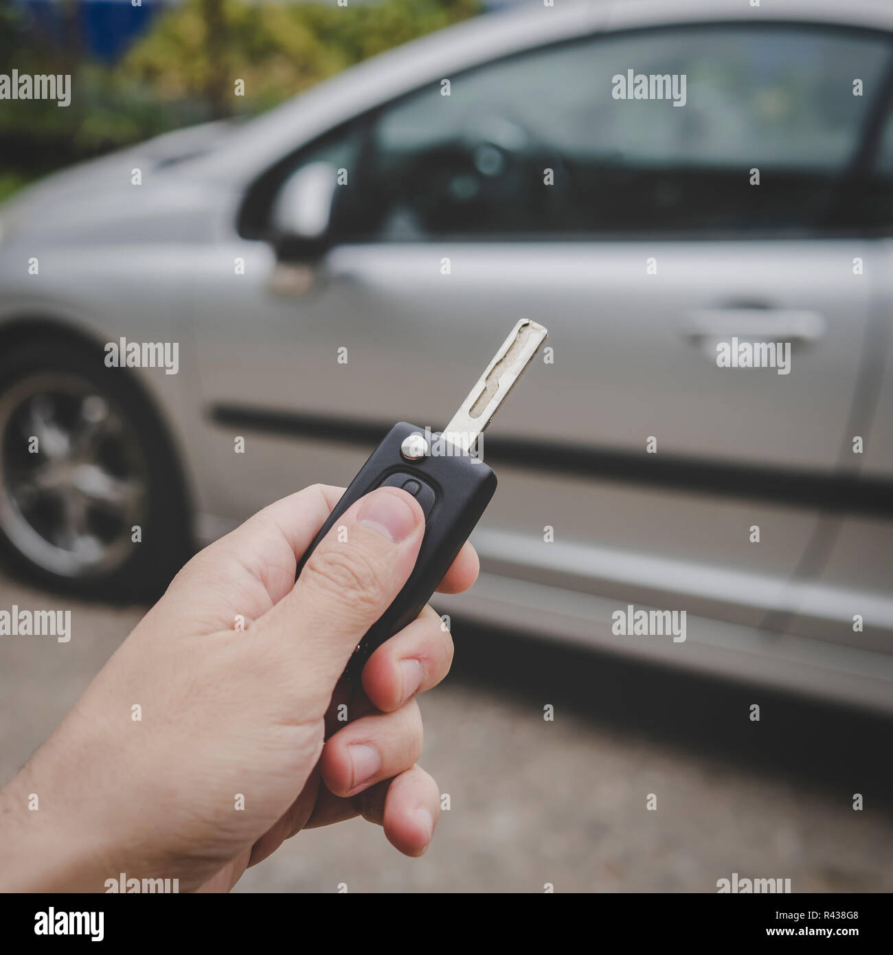 L uomo si apre la sua auto porta con il telecomando di controllo chiave. Maschio presse a mano sul veicolo di controllo remoto del sistema di allarme su auto parcheggiata sullo sfondo. Spegnimento Foto Stock