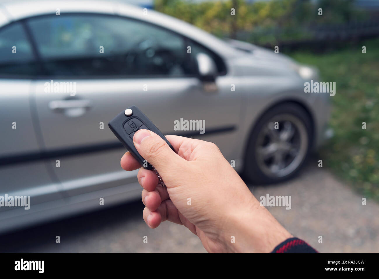 Man mano preme un pulsante sulla macchina remota di controllo contro la sfocatura auto. Nuovo proprietario di un veicolo si sblocca l'acquisto. Il concessionario di automobili mostra e apre il t Foto Stock