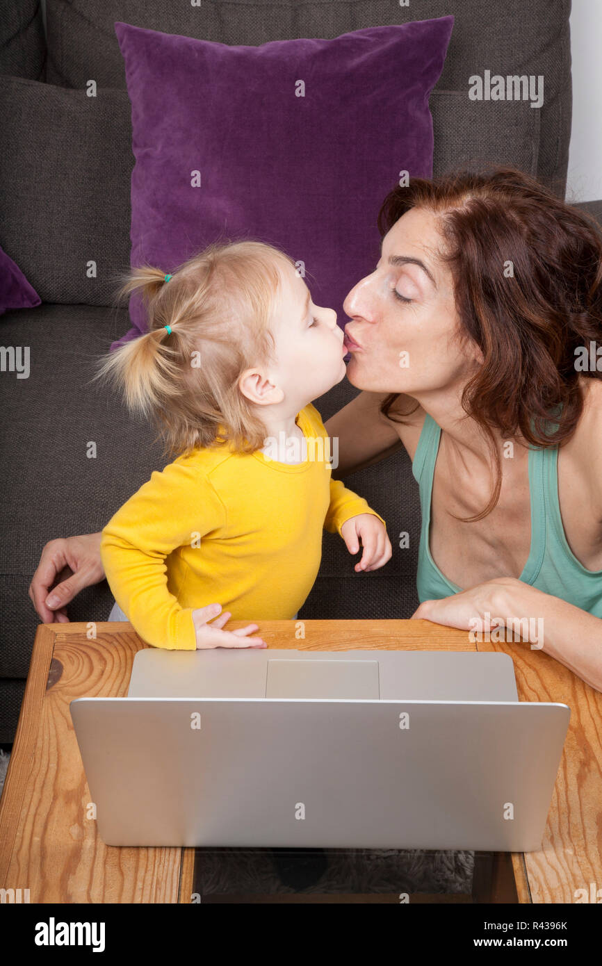 Il bambino e la mamma baciare con il computer portatile Foto Stock
