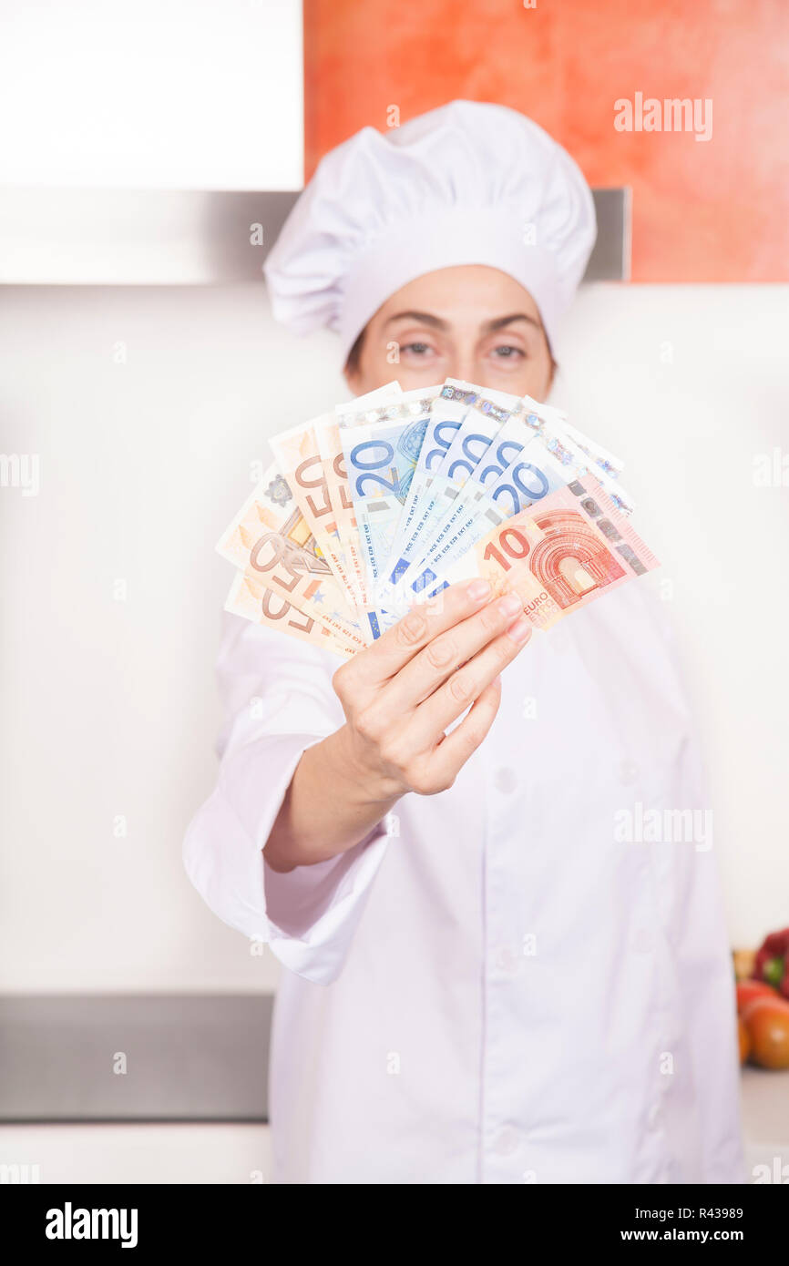 Mazzetta di banconote in euro in donna mani dello chef Foto Stock